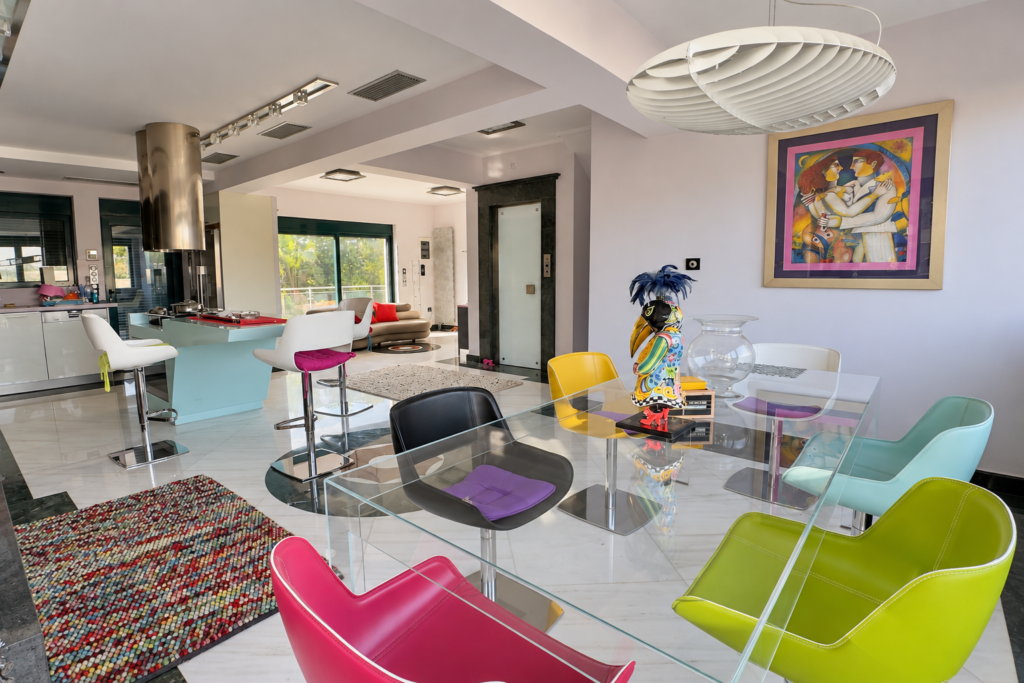 Smart Home Dining Area Glass dining table with colourful chairs and an open kitchen