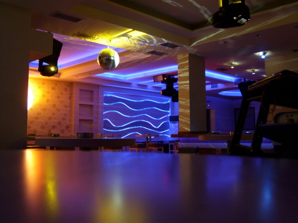 Beluga Beach Club — Εσωτερικό μπαρ με κρεμαστά φωτιστικά και φωτιζόμενες γραμμές στον τοίχο Εσωτερικό μπαρ με κρεμαστά φωτιστικά και φωτιζόμενες γραμμές στον τοίχο — Beluga Beach Club / Indoor bar with pendant lights and illuminated wall lines